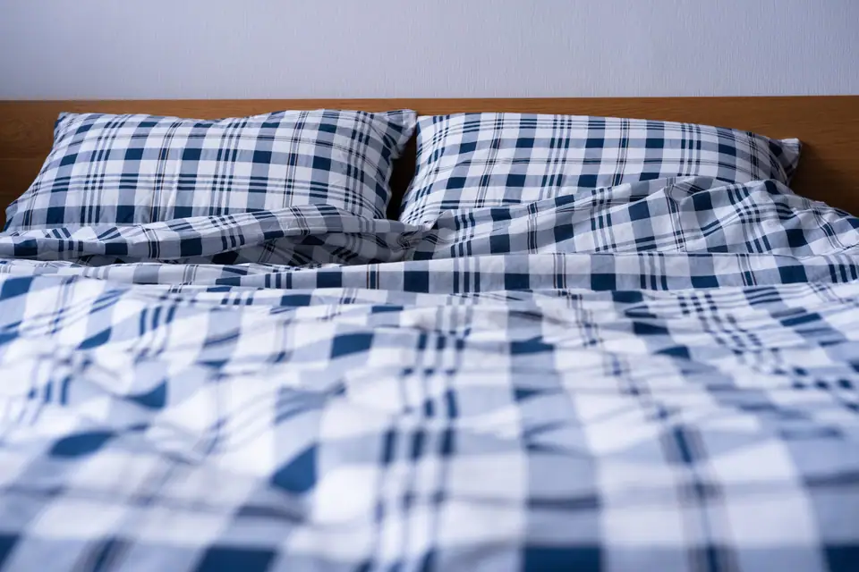 A double bed made with blue and white plaid bedding and matching pillows