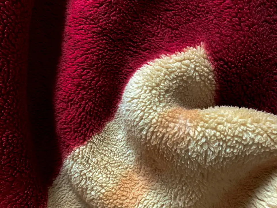 Close-up of red fleece and cream sherpa fabric showing the curly pile