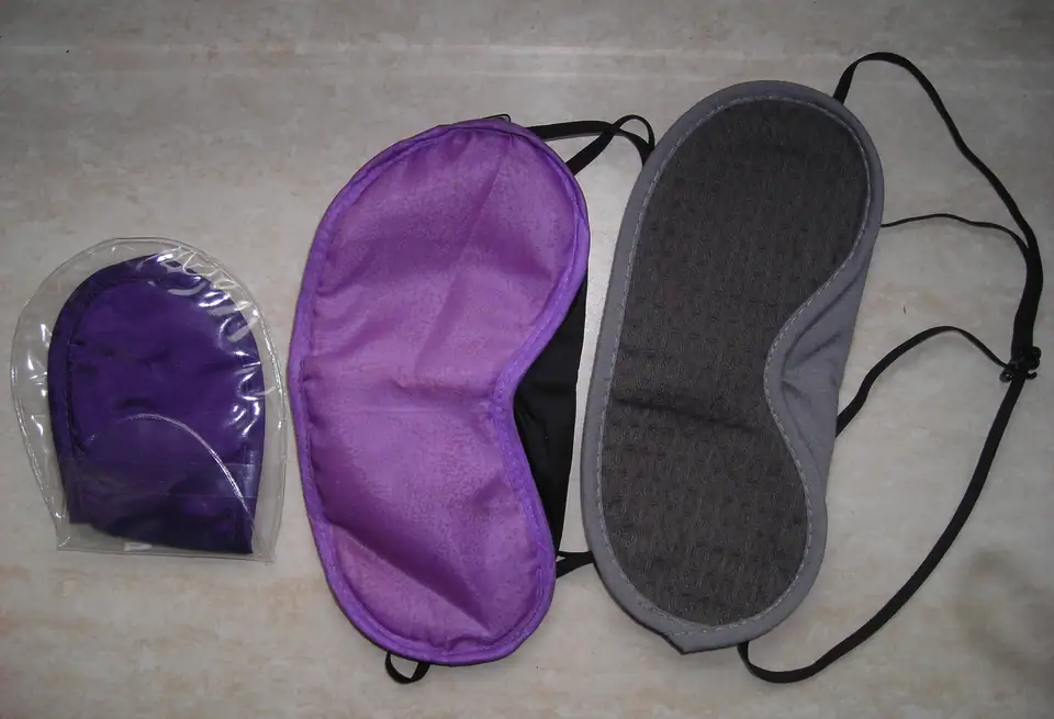 Three fabric sleep masks with elastic straps laid out side by side
